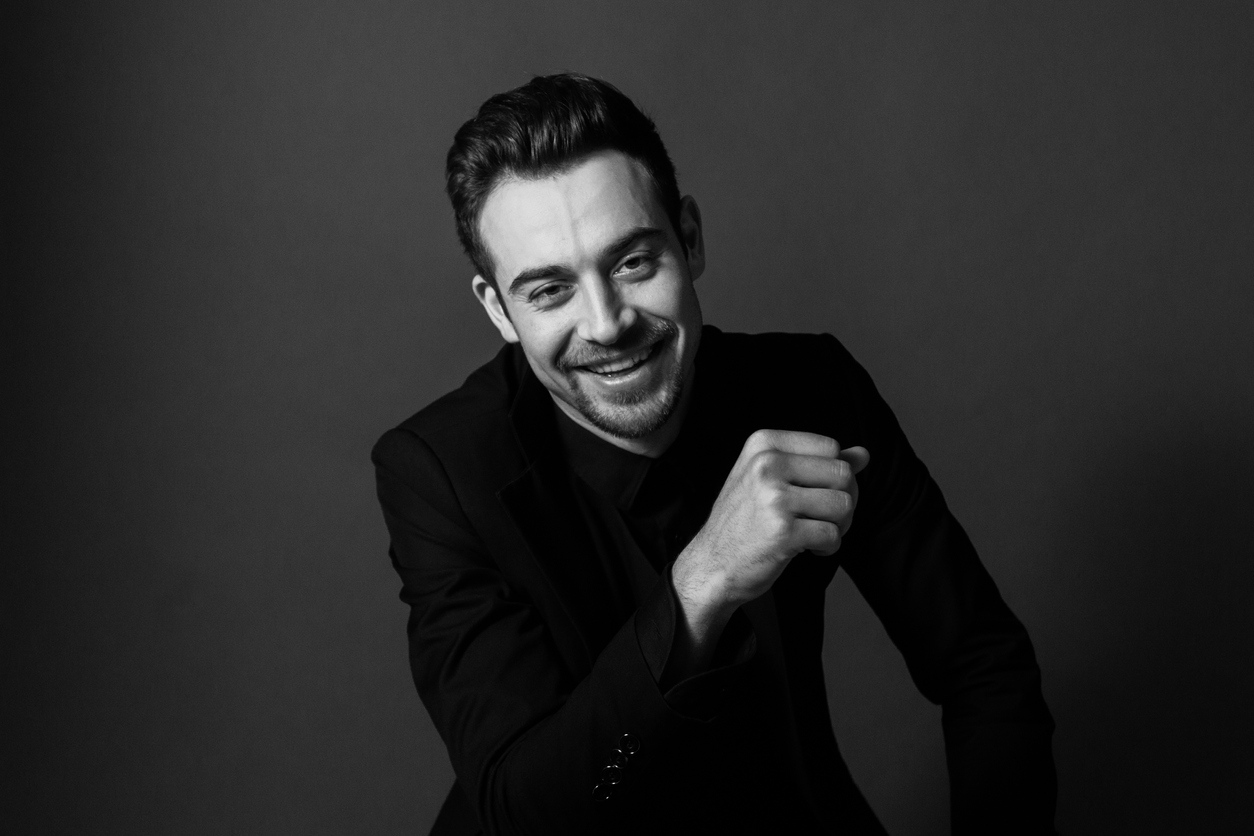 Black and white portrait of a young handsome man in a suit, smiling and looking at the camera